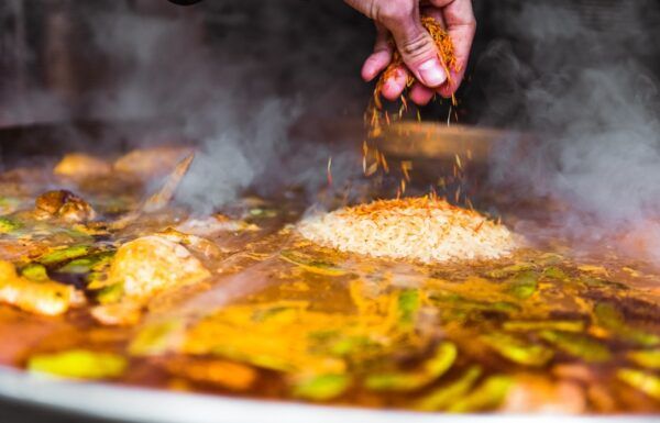 Paella köchelt und wird gewürzt